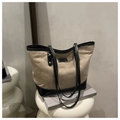 Detail der beigen Canvas-Einkaufstasche mit schwarzer gesteppter Ledertasche und Label - Khaki