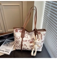 Detail van witte tote bag met rode doodle print en een beige pluche konijnenhanger - Bruin met Hanger