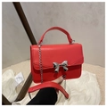 Detail of red mini square bag featuring silver bow buckle and elegant metal chain strap - Red