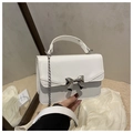 Close-up of white crossbody bag with silver bow ornament and metallic chain strap - White
