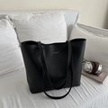 Bolso tote negro minimalista de cuero sintético para mujer sobre un sofá blanco - Negro