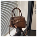 Detailed view of brown leather Boston bag featuring decorative metal buckle and woven charm - Brown