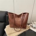Brown vintage leather tote bag with gold lettering on a soft knitted background - Brown