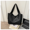 Detalle de bolso tote negro con hebilla dorada en un ambiente de oficina minimalista - Negro