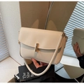 Close-up of minimalist cream white leather handbag with elegant gold metal buckle detail - Off White