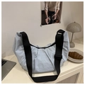 Detail of light blue pleated crescent bag with adjustable black shoulder strap on desk - Blue