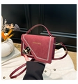 Dettaglio borsa quadrata bordeaux in pelle con cuciture bianche e chiusura dorata - Rosso