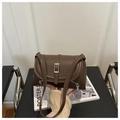 Detailed view of brown leather shoulder bag featuring silver metal buckle and side zippers - Coffee