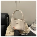 Detalle de un bolso tipo cubo crema con estuche interior sobre tejido de punto - Blanco