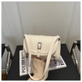 Detail view of cream leather shoulder bag with silver zipper and buckle on a chair - White