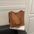 Klassische karamellbraune Beuteltasche mit Ziernähten und Doppelriemen auf Büchern - Hellbraun
