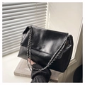 Detail of black pleated leather bag with silver chain strap and embossed fashion text - Black