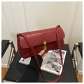 Detail of red crocodile texture handbag with gold cylindrical metal lock and strap - Red