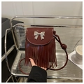 Detail of burgundy tassel bag with silver bow accent on an urban style shelf - Red