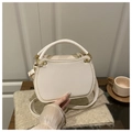 Detalle de elegante bolso de cuero crema con ribete dorado y diseño semicircular - Blanco
