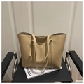 Detail of minimalist beige PU leather tote bag with slim handles on a chair - Khaki