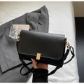 Detalle de bolso bandolera negro minimalista con hebilla dorada y textura de cuero mate - Negro