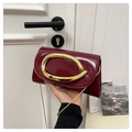 Detail of burgundy patent leather handbag featuring a large gold oval metal handle - Red