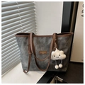 Detail van de grijze tote tas met gewassen textuur, bruine hengsels en pluche hanger - Met Hanger / Zwart