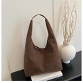 Close-up of brown suede hobo tote bag placed on books in a minimalist aesthetic setting - Coffee