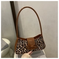 Leopard print underarm bag with brown shiny leather strap and bow detail shown indoors - Brown