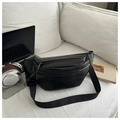 Chic black textured pebble faux leather sling bag with adjustable strap on white couch - Black