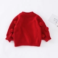 Détail d'un pull en maille rouge pour fille avec pompons festifs sur les manches - Haut de Pull Rouge