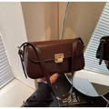 Detail der dunkelbraunen Leder-Schultertasche mit goldener Schnalle in warmer Atmosphäre - Kaffeebraun