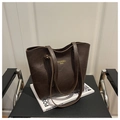 Detail einer tiefbraunen Leder-Einkaufstasche mit Goldlogo auf Designer-Stuhl - Kaffee Ohne Anhänger