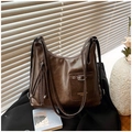 Detalle de bolso tote de cuero sintético marrón oscuro con bolsillos y correas múltiples - café