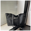 Close-up of black leather tote bag with circular quilted logo and vintage wax texture - Black