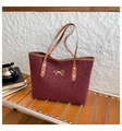 Detail of dark red leopard embossed tote bag with gold bow and brown leather handles - Red