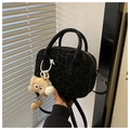 Detail of black leopard texture handbag with round handles and yellow plush charm - Black (With Charm)