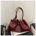 Vista detallada de bolso tote rojo vino brillante con pliegues sobre una silla negra - Rojo