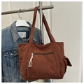 Detailansicht der braunen Cord-Tragetasche mit Seitentasche und Denim-Jacken-Styling - Braun