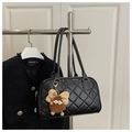 Detail van zwarte gewatteerde shopper met goudkleurige hardware en bruine pluche hanger - Zwart