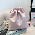 Mochila de nailon rosa claro con cordón para viajes sobre un banco de color beige - Rosa