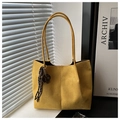 Detail of a yellow suede tote bag featuring slim round handles and a woven rope charm - Yellow With Pendant