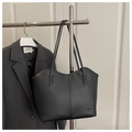 Detalle del bolso tote negro con textura de grano lichi y etiqueta de moda - Negro