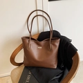 Sac fourre-tout marron en cuir grainé avec détail en métal sur une chaise en osier - Marron