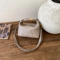 Close-up of taupe vintage handbag with vertical texture and gold hardware on a wooden table - Khaki
