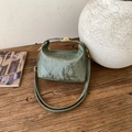 Detail of dark green retro handbag with vertical texture and gold hardware on wood - Green