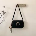 Detail of black suede shoulder bag featuring a large gold horseshoe buckle and baseball charm - With Pendant / Black