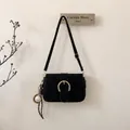 Detail of black suede shoulder bag featuring a large gold horseshoe buckle and baseball charm - With Pendant / Black