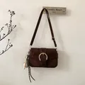 Detail of dark brown suede crossbody bag with gold round buckle and baseball charm - With Pendant / Brown