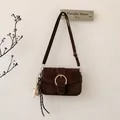 Detail of dark brown suede crossbody bag with gold round buckle and baseball charm - With Pendant / Brown