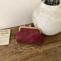 Detail of burgundy velvet handbag showing golden metal clasp and rich rabbit embossing - Red