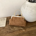 Detail of brown suede crossbody bag with gold handle and chain on a vintage table - Brown