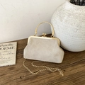 Close-up of vintage shell bag in beige suede with embossed patterns and gold metal handle - Khaki
