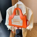 Detail van oranje lederen en geweven tas met BEPRO-borduurwerk en gouden fittingen - Oranje